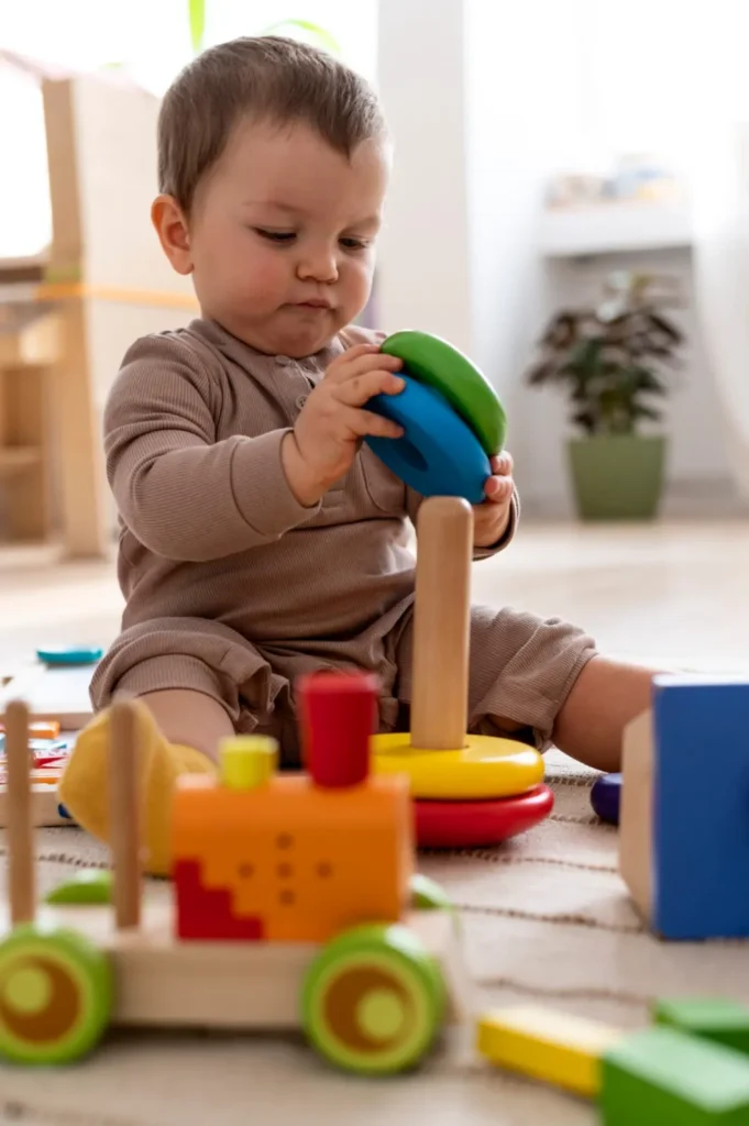Bébé qui empile des anneaux en bois colorés