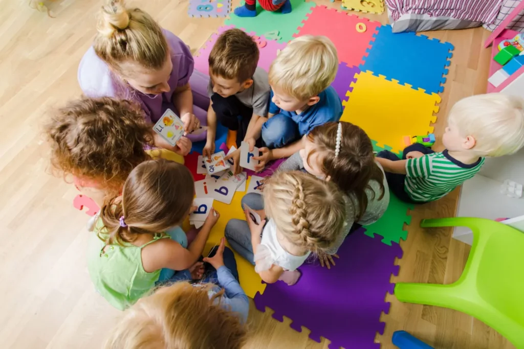 Enfants assis en cercle avec une adulte autour de cartes illustrées