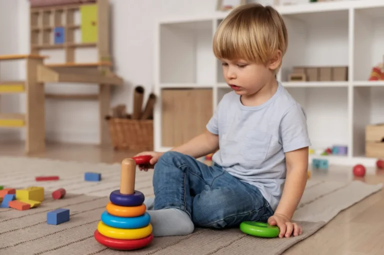 Petit garçon qui empile des anneaux colorés sur un tapis