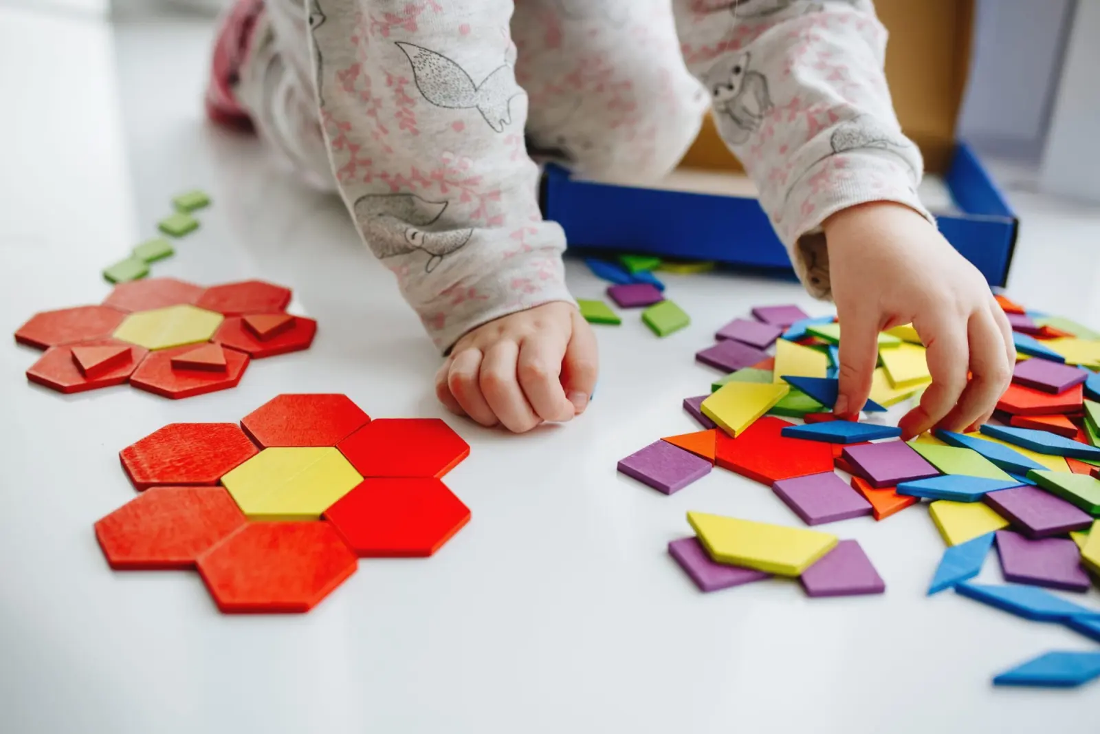 Mains d’enfant qui composent des fleurs avec des formes en bois