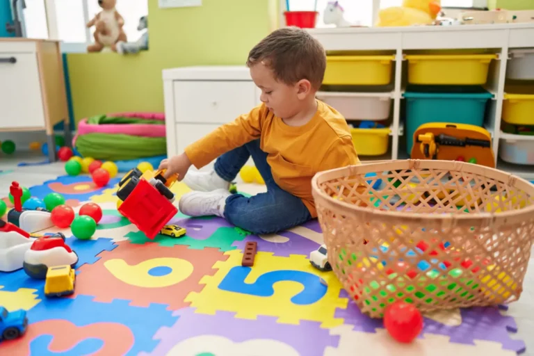 Petit garçon qui joue avec des véhicules sur un tapis coloré