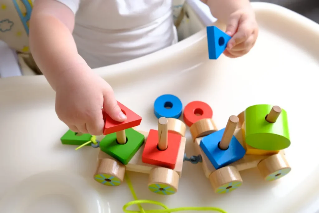 Mains d’enfant qui enfilent des formes en bois sur un petit train